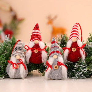 Close-up of four knitted Christmas gnomes with wooden buttons on pine branches