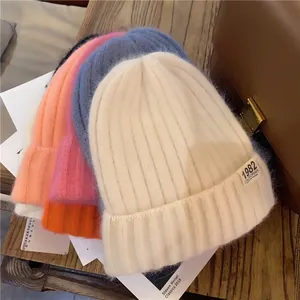 Detail of ribbed knit beanies with 1982 California label on a wooden surface