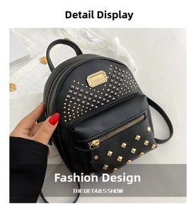 Detail of a black mini backpack with gold studs in V-shape and front zipper pocket