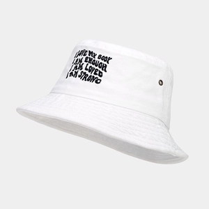 Détail d'un bob en coton blanc avec broderie texte noire et œillet métallique latéral