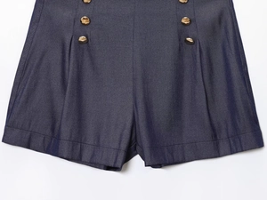 Gros plan d'un short en jean bleu marine à taille haute avec boutons dorés sur les côtés