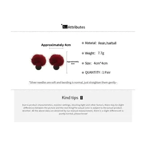 Détail de boucles d'oreilles boules rouges avec base en résine et aiguilles en argent