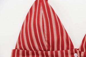 Detail of red and white striped fabric with a white round button and stitch texture