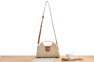 Detail of woven straw handbag featuring brown leather trim and golden metal clasp