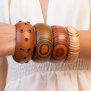 Close-up of four stacked wooden bracelets with rivet details and natural grain texture