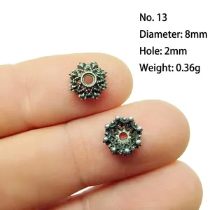 Macro view of an 8mm vintage silver alloy hollow flower spacer bead on a finger