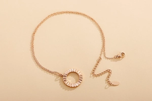 Detail of rose gold double-layer necklace with sun pendant, lobster clasp, and extension chain
