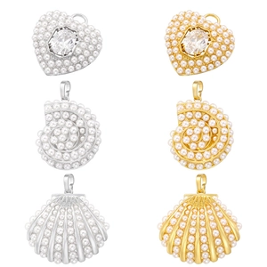 Close-up of elegant pearl-encrusted heart and seashell pendants in gold and silver