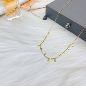 Detailed view of a gold titanium teardrop necklace on a soft white faux fur background