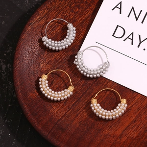 Macro view of gold and silver vintage hoop earrings with micro pearls on wood