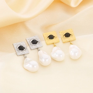 Detail of square hammered evil eye earrings with irregular pearls in gold and silver