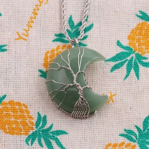 Close-up of tree of life wire-wrapped aventurine crescent moon necklace on linen