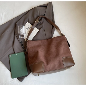 Detail of vintage brown suede tote bag with leather patchwork and sturdy shoulder strap