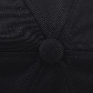 Close-up of the top button and stitched seams on a black cotton baseball cap