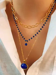 Detailed view of triple-layered necklace with gold chains and blue gemstone pendants