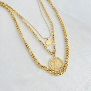 Chic triple-layered gold coin necklace with portrait pendant on white fabric background