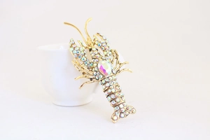 Close-up of a sparkling crystal lobster pendant with colorful rhinestones on a gold base