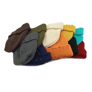 Close-up of knit beanies with metallic rings, safety pins and distressed details