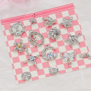 Flat lay of silver alloy charms including stars, moons and hearts on pink checkered card