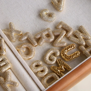 Gros plan de pendentifs lettres bulles plaqués or 18 carats sertis de zircons cubiques