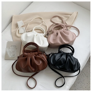 Flat lay of pleated cloud bags in white, pink, brown and black with circular handles