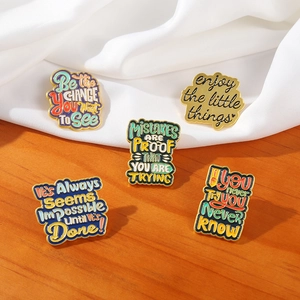 Detail view of five vintage inspirational metal enamel pins on textured fabric background