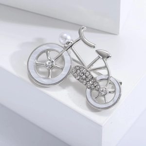 Detail of silver bicycle brooch with inlaid pearl, crystals and white shell texture