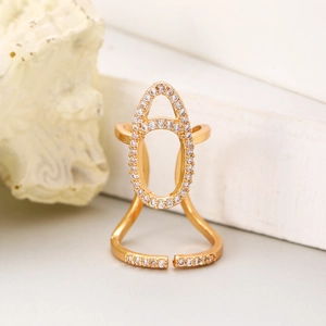 Macro detail of gold-plated nail ring with sparkling cubic zirconia on white stone