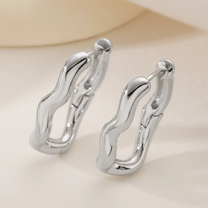 Irregular wavy silver hoops in polished metal with a minimalist geometric design
