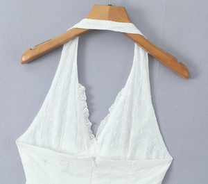 Detail of white floral lace cutout patterns on sleeveless halter V-neck dress