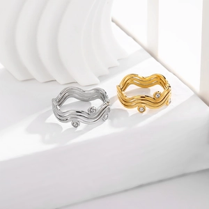 Detail of wave-layered stainless steel rings with sparkling zircon pavé in gold and silver