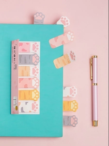 Detail of cute cat paw sticky notes used as page markers on a notebook with pink pen