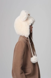 Close-up of soft plush bucket hat with cute bear ears in cream white on a female model