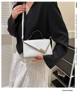 Close-up of white crocodile pattern envelope bag with a golden turn-lock on street model