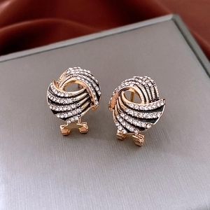 Macro shot of gold-plated wing earrings with sparkling crystals and black enamel stripes