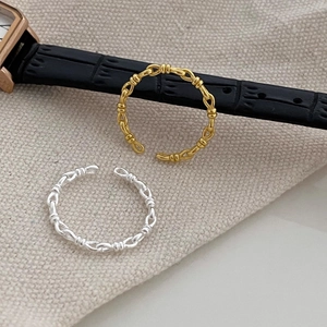 Close-up of gold and silver S925 sterling silver woven knot rings on grey fabric