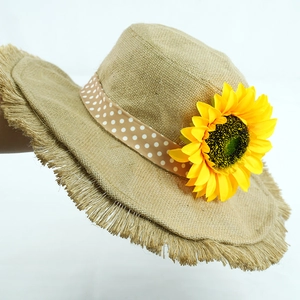 Close-up of linen sun hat with frayed edge, sunflower decor, and polka dot ribbon