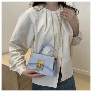 Blue crossbody bag featuring geometric gold buckle and detachable chain strap detail