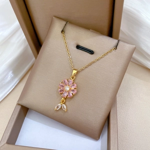 Macro shot of pink flower pendant with white crystal leaves on a gold titanium chain