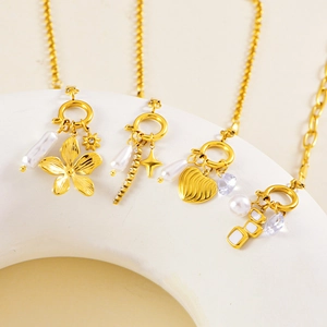 Detail of four gold necklaces featuring floral, star, and heart charms with pearls and crystals