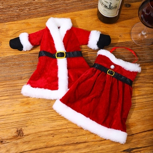 Detail of red velvet Christmas wine bottle outfits with Santa jacket and skirt on a table