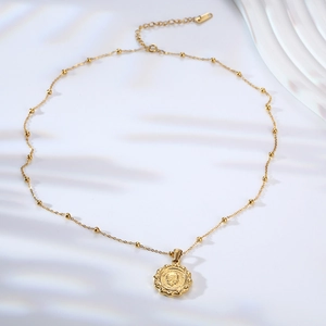 Close-up of golden coin necklace with Elizabeth II relief and beaded chain detail
