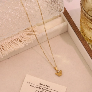 Detailansicht einer goldenen Engel-Halskette mit klarem Zirkon auf einem cremefarbenen Tablett