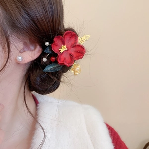 Macro detail of Chinese style red flower hair clip with golden leaves and pearl accents