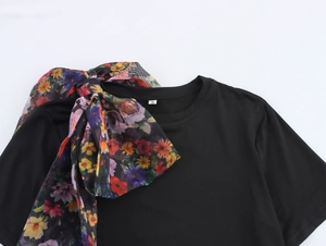 Detail of round neck top featuring large colorful floral organza bow at the neckline
