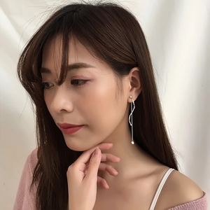 Detail of silver wavy fringe drop earrings with small pearls on model side view