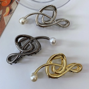 Detail of twisted metal shark clips in gold, silver and grey with pearl accents