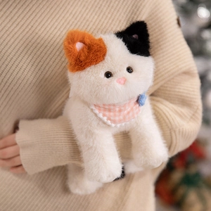 Realistic tricolor calico cat plush toy with pink plaid scarf held against a sweater