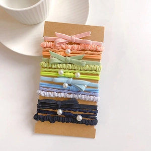 Flat lay of colorful hair ties with pearls and bows on a brown cardboard holder