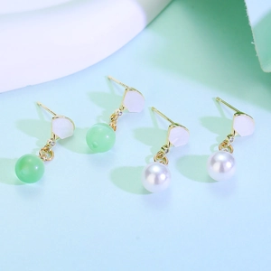 Detail of fan-shaped gold earrings with green aventurine and white pearl pendants